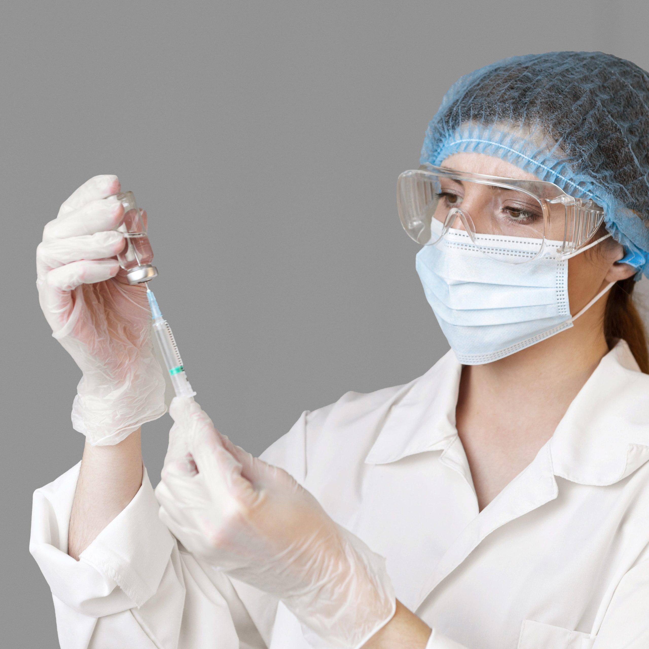 female-scientist-with-safety-glasses-hair-net-holding-syringe