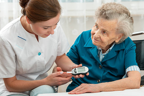 Female nurse measuring blood glucose level of senior woman